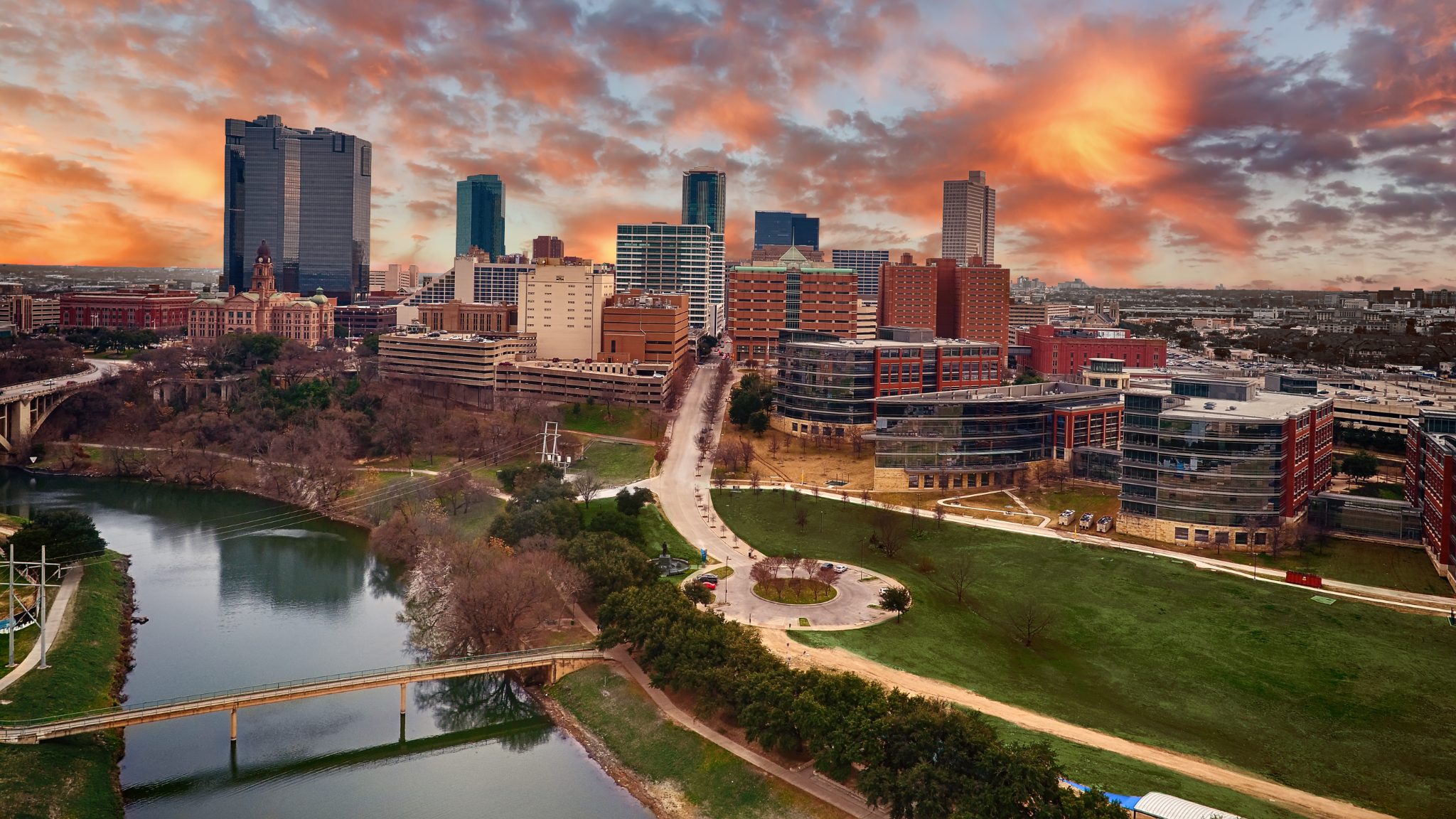 Sunset over downtown skyline with river, bridges, and green park space