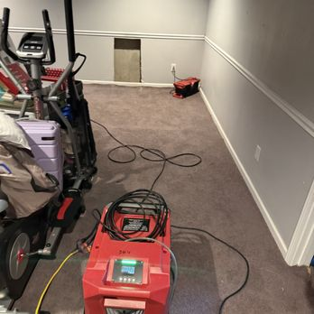 Dehumidifier drying carpet in a basement workout room