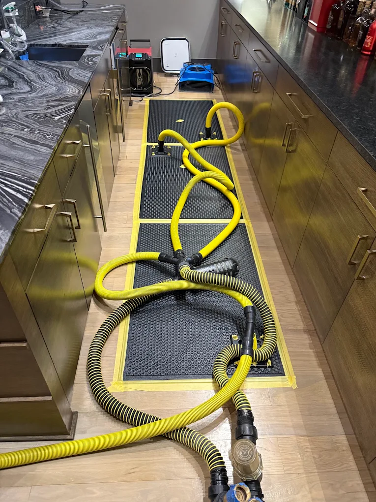 Extraction hoses staged on a hardwood floor during a sewage cleanup