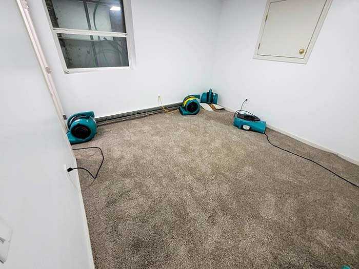 Air movers drying a flooded room down to the slab