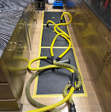Drying mats and hoses extracting water from a hardwood kitchen floor