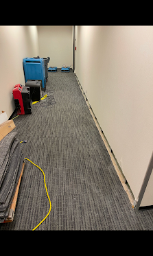 Commercial office hallway drying with air movers and removed baseboards